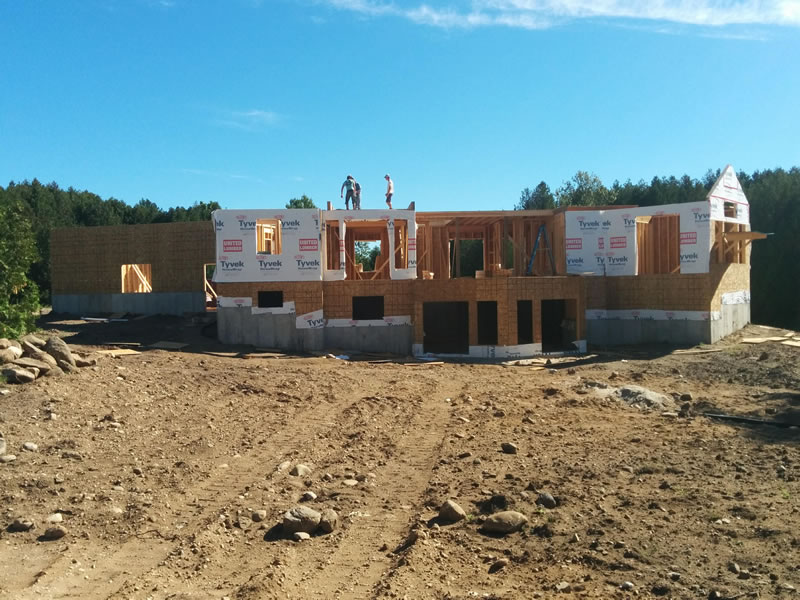 Wall framing going up on an A&R home, with a crew working on the upper floor