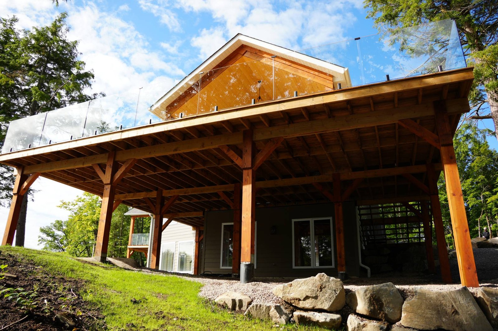 Heavy timber posts carrying a covered deck and the house above it, each post taking its load straight down to the ground, the kind of point load concrete footings are sized to spread